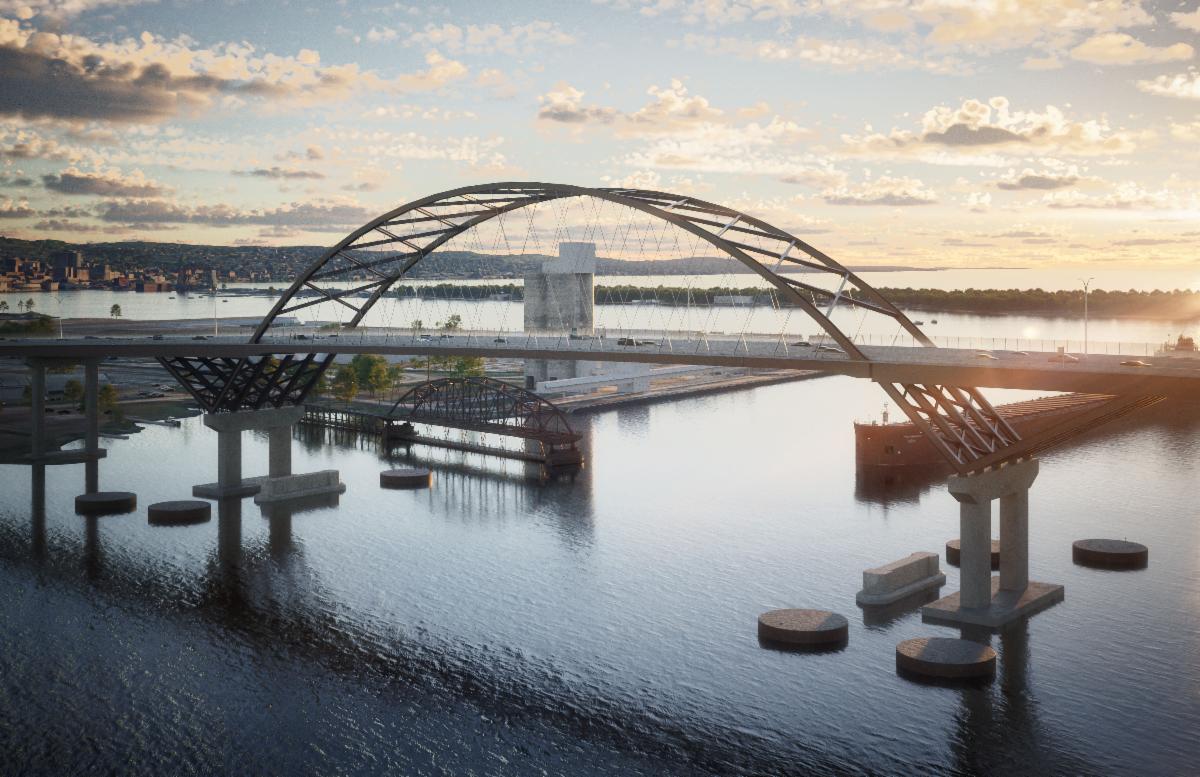 Modern curved arch bridge spanning a calm river at sunset, with reflection in the water and distant city silhouettes fluidly visible in the background.